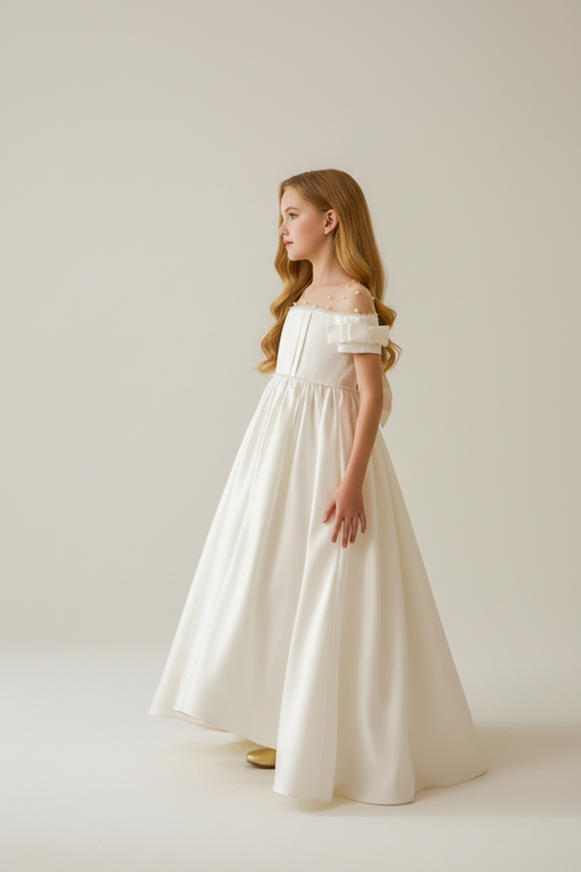 Young girl in a white dress standing in a room with decorative elements.